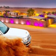 Premium desert safari Dubai 4x4 vehicle driving over golden sand dunes in front of belly dance stage