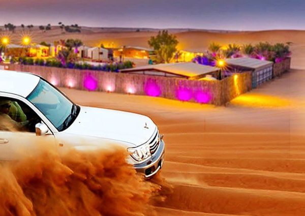 Premium desert safari Dubai 4x4 vehicle driving over golden sand dunes in front of belly dance stage