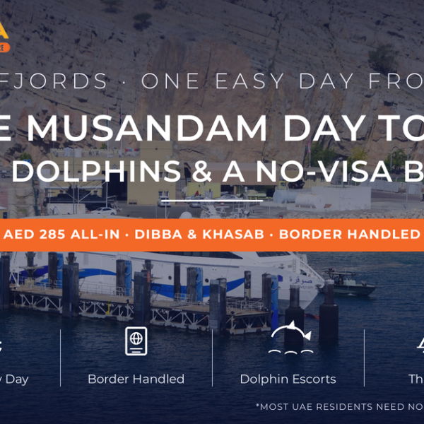 Khasab harbour in Musandam Oman with a catamaran ferry docked beneath sheer Hajar mountain cliffs - Musandam tour from Dubai day-trip guide with dhow cruise and border pass by Mayra Tours